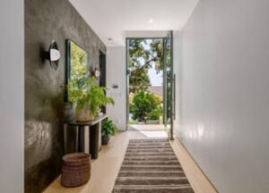 Bright hallway with plants and a glass door opening to greenery.