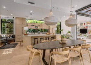 Modern open kitchen and dining area with wooden furniture and pendant lights.