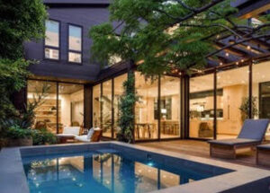 Modern house with a glass exterior and a pool at dusk.
