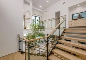 Modern staircase with glass railing and indoor plants.