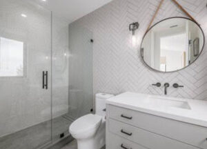 Modern white bathroom with glass shower and round mirror.