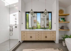 Modern bathroom with double sinks and large windows.